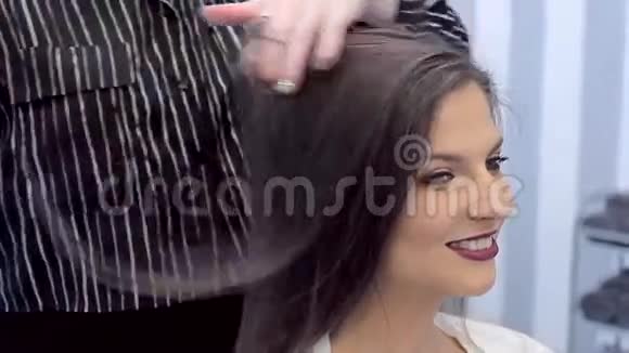 年轻漂亮的女孩微笑而理发师工作她的头发视频的预览图