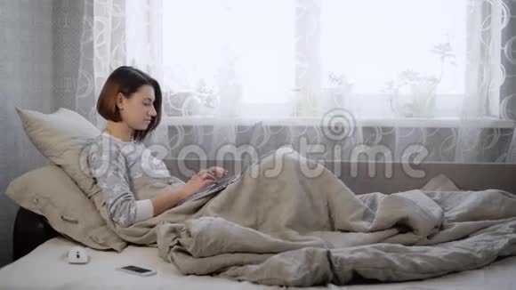 美丽的黑发女人穿着睡衣躺在床上家里的卧室里有笔记本电脑小女孩个子矮视频的预览图