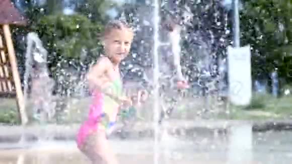 一个七岁的女孩穿着泳衣在喷泉里洗澡到处跑喷射玩得开心在炎热的夏天慢慢视频的预览图