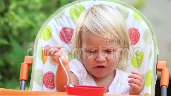 小女孩坐在椅子上用勺子吃芒果视频的预览图