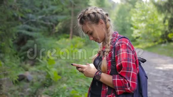 快乐女孩站在森林里在智能手机上发短信视频的预览图