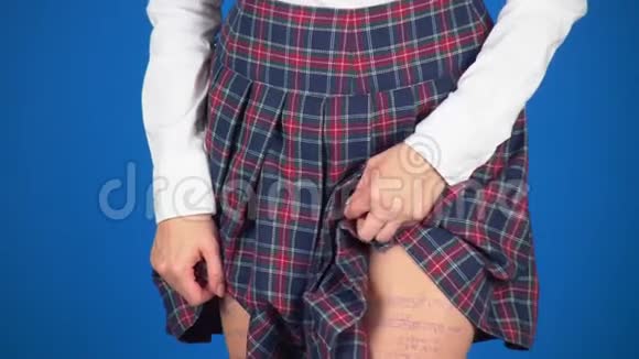 十几岁女孩的剪报写在臀部隐藏在裙子下的备忘单4k特写蓝色背景慢镜头视频的预览图
