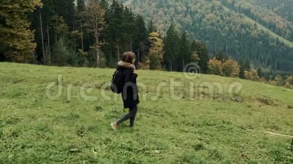 镜头跟随年轻女孩徒步旅行者走在户外的背景山区景观视频的预览图