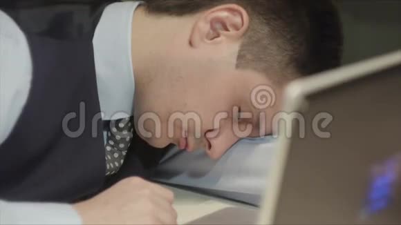 年轻英俊的男人躺在桌子上睡觉然后他突然醒来开始在电脑上工作视频的预览图