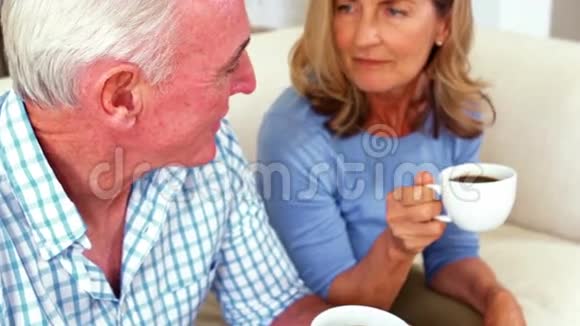 在客厅喝杯咖啡时微笑的老夫妇在互动视频的预览图