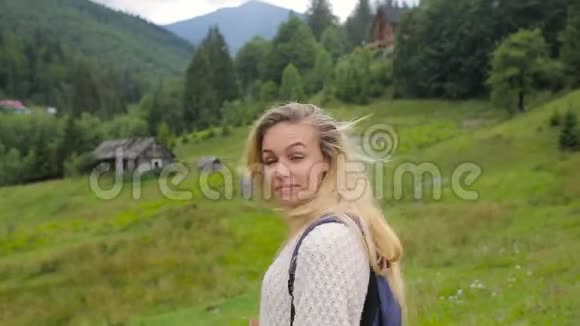 美丽的女孩在镜头前摆姿势在森林和山村的背景上微笑视频的预览图