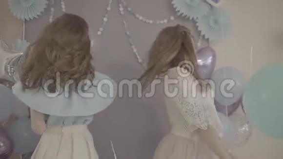 两个兴奋的年轻迷人的女人穿着漂亮的漂亮裙子手里拿着气球在镜头前微笑着转过身来视频的预览图