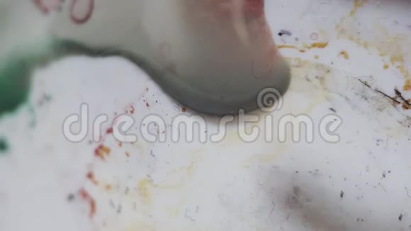 在白色塑料脏调色板上用水混合刷橙色漆视频的预览图