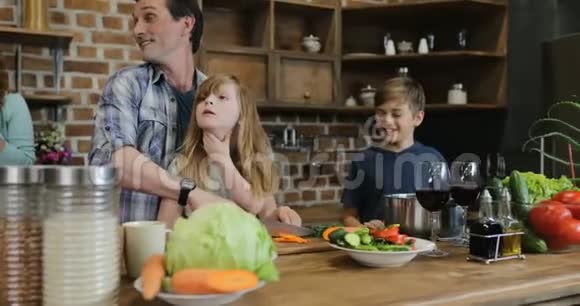 幸福的家庭在厨房准备食物妈妈看着爸爸和孩子一起在家做饭视频的预览图