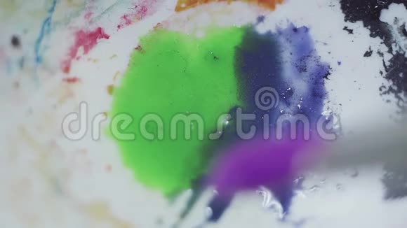在白色塑料调色板上涂上蓝色绿色和紫色的水漆视频的预览图
