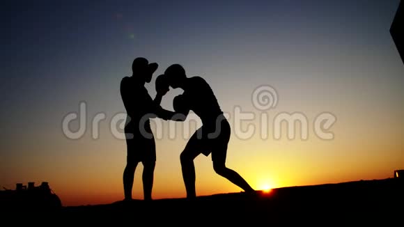 两个黑暗的男性人物日出时逆光拳击拳击拳击拳击训练一对技巧视频的预览图
