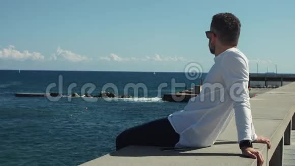 阳光明媚的一天坐在海前的人视频的预览图
