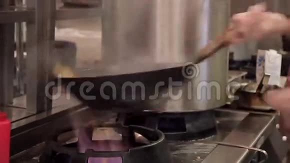 在室内工业厨房的炉子上用炒锅炒烤视频的预览图