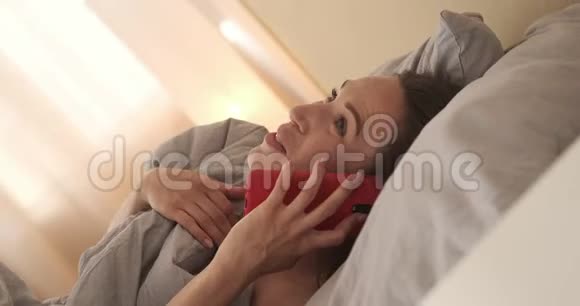 快乐的女人在床上用手机说话视频的预览图