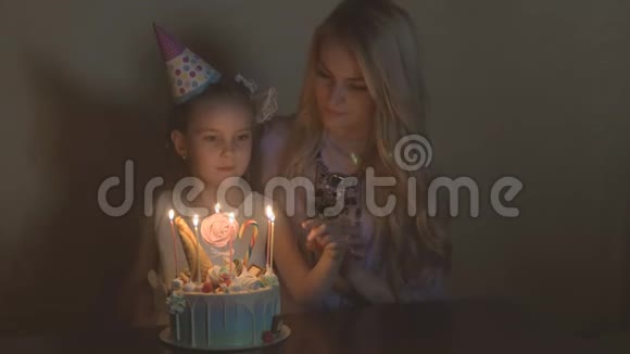 母女俩在生日蛋糕上吹蜡烛一个小女孩的生日在节日里的生日女孩视频的预览图
