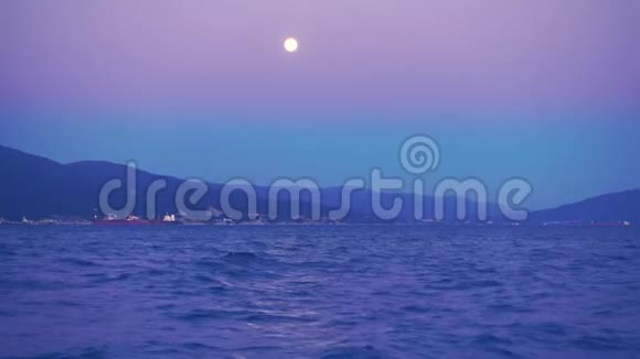 美丽的夜晚和满月越过港口城市船在远处视频的预览图