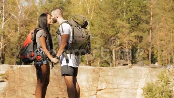 一对年轻的徒步旅行者在悬崖边亲吻视频的预览图