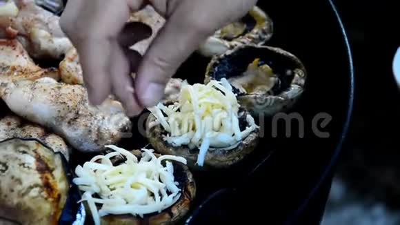 在烧烤时将磨碎的奶酪加入蘑菇帽中视频的预览图