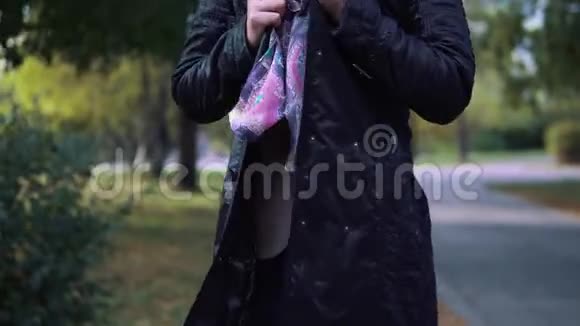 那女孩在秋天的公园里冻僵了年轻女子裹着围巾在他手上呼气取暖视频的预览图