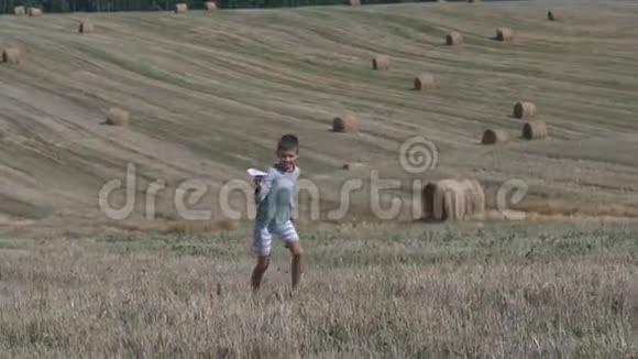 快乐的少年男孩在收获的田野背景下玩纸飞机视频的预览图
