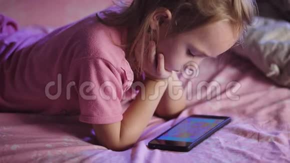 孩子躺在床上女孩准备睡觉在睡觉前孩子看着动画片视频的预览图