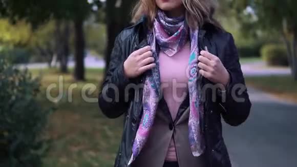 那个年轻的女人冷了冷把自己裹在围巾里秋天公园里冻僵的女孩视频的预览图