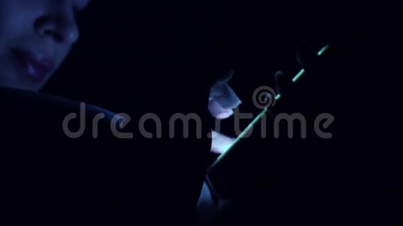 女孩的手在黑暗中触摸手机屏幕蓝色4K特写视频视频的预览图
