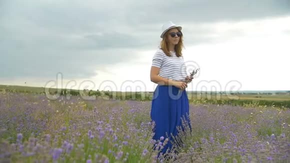 戴帽子的女孩正走在薰衣草的田野上视频的预览图