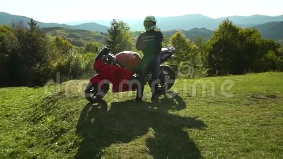 一个骑摩托车的人带着摩托车在山上的年轻帅哥他站在摩托车旁边视频的预览图