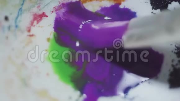 在白色调色板上涂上蓝绿紫的水漆视频的预览图