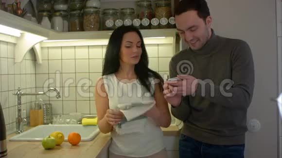 一对幸福的夫妇在家厨房边做饭边用智能手机聊天视频的预览图