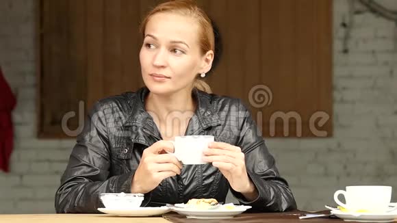 漂亮的女人在夏天的露台上吃午饭特写女孩喝咖啡或茶慢动作视频的预览图