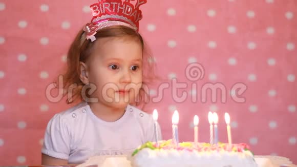 生日快乐可爱的孩子许愿在聚会上吹灭蛋糕上的蜡烛有趣的小女孩粉红色背景视频的预览图