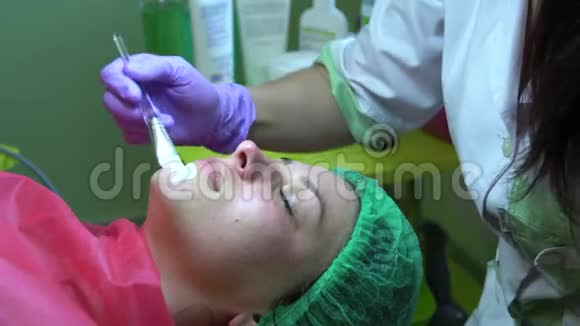 一个年轻的女孩在一个接待与美容师美容师把面具戴在脸上视频的预览图