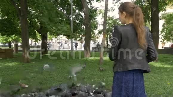 一个悲伤的漂亮女孩在公园里喂鸽子视频的预览图