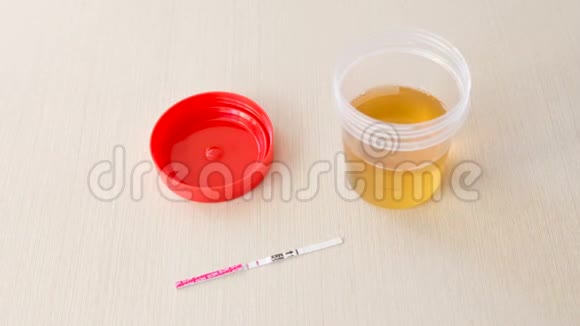 阳性妊娠试验结果两条在桌子上旁边的尿罐视频的预览图