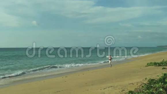 健康年轻女人沿着海滩奔跑视频的预览图