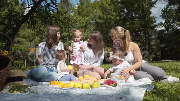 年轻的母亲带着孩子坐在公园里野餐视频的预览图
