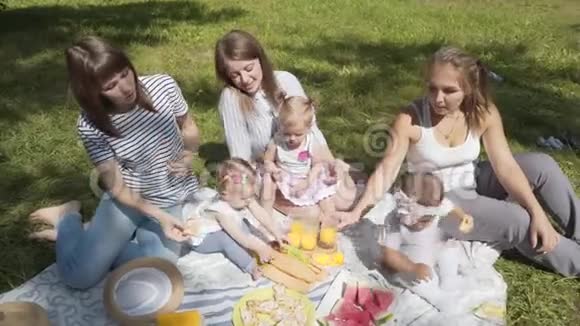年轻的母亲带着孩子坐在公园里野餐视频的预览图