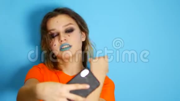 一个留着长发的快乐女孩笑着双手捧着她的脸站在室内被隔绝在蓝色之外视频的预览图