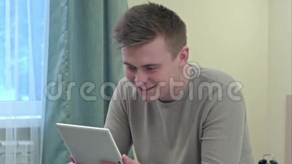 年轻人在家里通过平板电脑打视频电话视频的预览图
