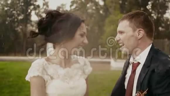 可爱的特写镜头在公园的背景下微笑的新婚夫妇在雨中接吻视频的预览图