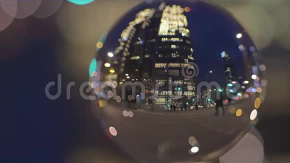 市中心的道路交通和人们在晚上穿过街道通过玻璃球观看视频的预览图