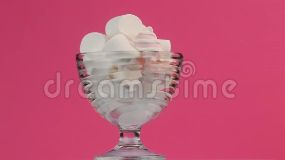 不同的毛茸茸的甜棉花糖在粉红色背景的玻璃碗里视频的预览图