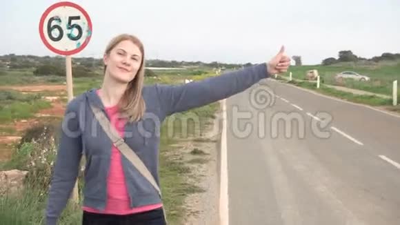 年轻快乐的女人走在乡间的路上搭便车寻找乘车开始旅程视频的预览图
