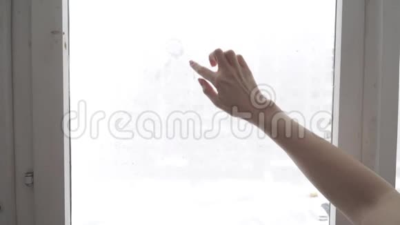 手在冷雾的窗户背景上画出爱的心特写图像视频的预览图