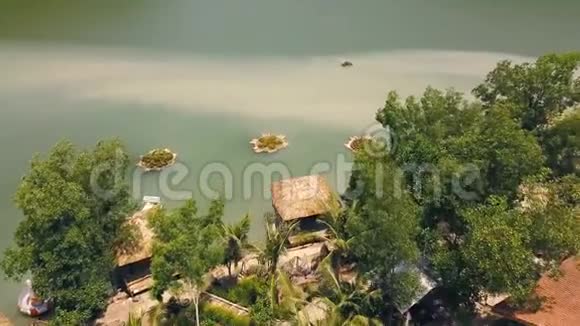 热带平房与茅草屋顶和船码头在海岸绿湖度假酒店山上鸟瞰平房视频的预览图