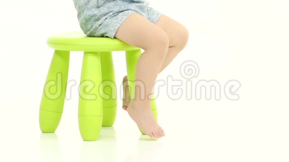 孩子坐在绿色的椅子上拿着糖果白色背景慢动作视频的预览图