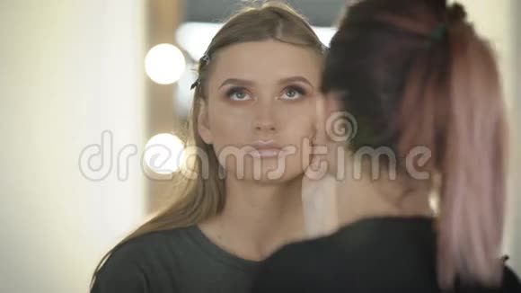 美容店化妆过程中的年轻专业封面女郎年轻的脸上涂着眼影视频的预览图