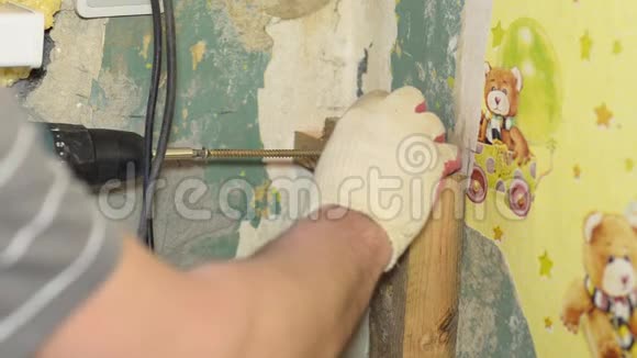 工人用电动螺丝刀把大的螺丝拧进墙里视频的预览图